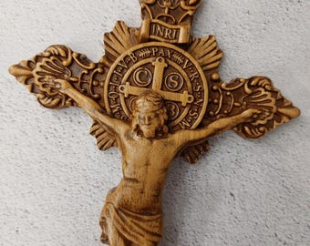 May include: A wooden crucifix with a carved figure of Jesus Christ. The crucifix features a decorative crown and a circular medallion with the inscription "INRI" and "PAX" in Latin.