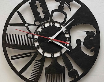 May include: Black and white clock with a barber theme. The clock face is surrounded by various barber tools, including a comb, scissors, a razor, and a hair clipper. The clock hands are red and white.