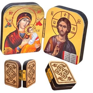 May include: Wooden religious icon box featuring images of religious figures. The box is hinged and opens to reveal the icons. The exterior of the box has a decorative carved design. The icons are painted with vibrant colors and gold accents.