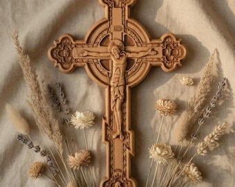 Può includere: Un crocifisso in legno intagliato raffigurante Gesù Cristo, con motivi dettagliati e floreali. La croce è circondata da fiori ed erbe secche, creando un'estetica naturale. Lo sfondo è un tessuto neutro e strutturato.