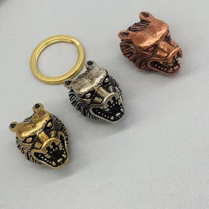 May include: Three wolf head keychains in different metal finishes: gold, silver, and copper. The keychains are detailed with sharp teeth and furrowed brows.