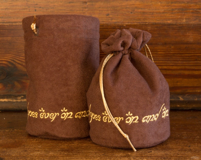 May include: Two brown velvet pouches with gold embroidery. The pouches have the text "goes ever on and on" embroidered on them.