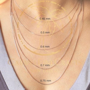 May include: Five silver chains of different thicknesses on a person's neck. The chains are labeled with their thickness in millimeters: 0.45 mm, 0.5 mm, 0.6 mm, 0.7 mm, and 0.75 mm.