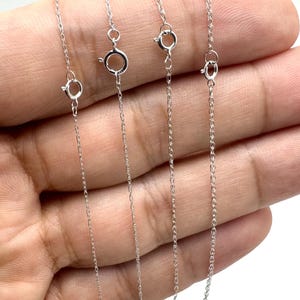 May include: Four silver-colored metal chains with spring ring clasps, displayed in varying thicknesses labeled as 0.7mm, 0.8mm, 1.0mm, and 1.2mm. Each chain features a delicate link design and a circular fastener, presented in a vertical orientation.