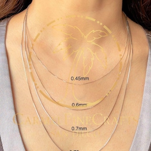 K&ouml;nnte beinhalten: Darstellung von vier filigranen Silberketten, jede mit einer anderen St&auml;rke: 0,45 mm, 0,6 mm, 0,7 mm und 0,75 mm. Die Ketten werden am Hals einer Person gezeigt, um die verschiedenen Gr&ouml;&szlig;en und Stile zu pr&auml;sentieren.