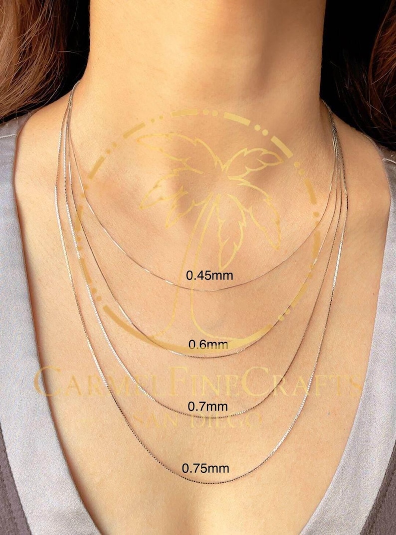 K&ouml;nnte beinhalten: Darstellung von vier filigranen Silberketten, jede mit einer anderen St&auml;rke: 0,45 mm, 0,6 mm, 0,7 mm und 0,75 mm. Die Ketten werden am Hals einer Person gezeigt, um die verschiedenen Gr&ouml;&szlig;en und Stile zu pr&auml;sentieren.