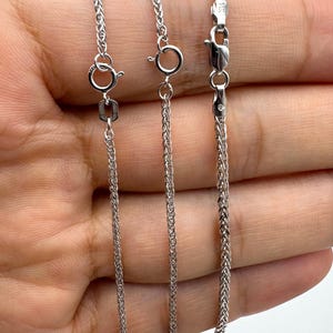 May include: Three silver-toned wheat chains with varying widths of 1.5mm, 1.75mm, and 2.3mm. Each chain features a polished metallic finish, a circular spring ring clasp, and a small rectangular tag near the closure, displaying clear size labels.