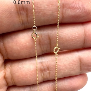 Peut inclure: Deux chaînes en métal doré avec fermoirs à ressort. La chaîne de gauche est étiquetée 0,8 mm et celle de droite 1,0 mm. Les chaînes présentent des maillons ovales entrelacés délicats qui forment un cordon de bijoux continu, fin et flexible.