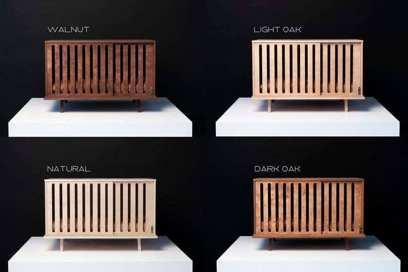 May include: Four wooden cots with vertical slats and sliding panels, labelled Walnut, Light Oak, Natural, and Dark Oak. Each cot features a rectangular frame, a flat base, and short legs, showcasing distinct wood tones ranging from light to dark.