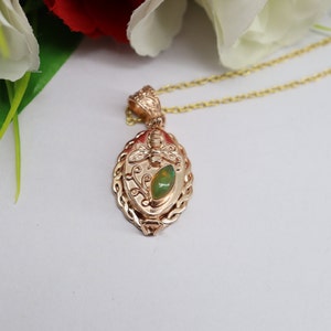 May include: A gold pendant necklace with a green opal stone and a dragonfly design. The pendant is oval shaped and has a detailed design.