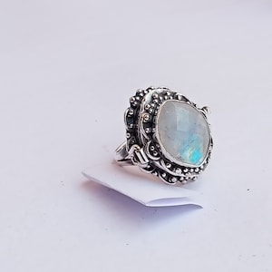 May include: A silver ring with a large, oval-shaped moonstone set in a detailed, ornate design.