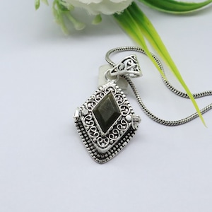 May include: A silver pendant necklace with a dark green gemstone set in a filigree design.