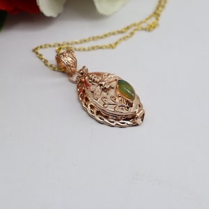 May include: A gold-tone necklace with a pendant featuring a green opal stone and a bee design. The pendant is oval-shaped and has a detailed floral pattern.