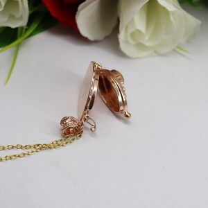 May include: A gold-toned locket necklace with a delicate chain. The locket is open, revealing a smooth, empty interior.
