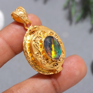 Op de afbeelding: Gouden medaillon hanger met een iriserende edelsteen in het midden. Het medaillon heeft een sierlijk ontwerp met ingewikkelde details.