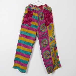 May include: Colorful, patterned pants with a mix of magenta, teal, and gold stripes and floral designs. The pants are made of a lightweight fabric and are hanging on a hanger. The pants have a relaxed fit.