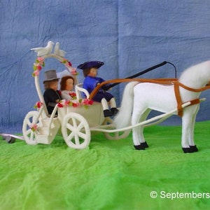 Op de afbeelding: Een witte paardenkoets met een wit paard dat hem trekt. De koets is versierd met witte duiven en roze bloemen. Er zitten drie figuren in de koets, twee met hoeden en een met een blauwe jurk.