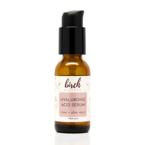 May include: A brown glass bottle with a black pump dispenser. The label reads "Birch Sisters" and "Hyaluronic Acid Serum rose + aloe vera 1 fluid ounce."