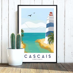 May include: A framed art print featuring a coastal scene with a lighthouse, ocean, and palm trees. The print has a blue and white lighthouse with a red top. The word "CASCAIS" is printed in white letters at the bottom.