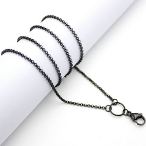 Könnte beinhalten: Eine schwarze Kettenkette mit einem Karabinerverschluss. Die Kette ist aus Metall und hat eine matte Oberfläche.
