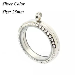 Könnte beinhalten: Silberner Anhänger mit einem klaren Glaseinsatz und einer Reihe von klaren Strasssteinen am Rand. Der Anhänger hat einen Durchmesser von 25 mm.