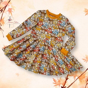 Peut inclure: Une robe à manches longues avec une bordure jaune et un imprimé de hiboux colorés. La robe a une jupe évasée et est faite d'un tissu doux et confortable.