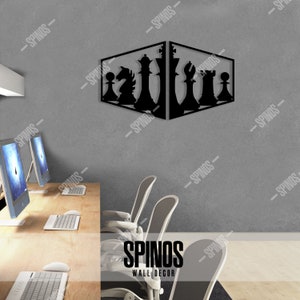 May include: Black metal wall decor featuring a chess set design. The chess pieces are arranged in a diagonal line, with the king and queen in the centre. The decor is mounted on a grey wall in an office setting.