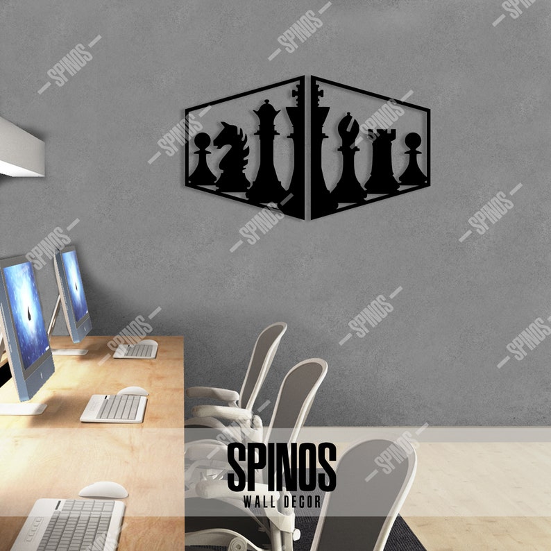 May include: Black metal wall decor featuring a chess set design. The chess pieces are arranged in a diagonal line, with the king and queen in the centre. The decor is mounted on a grey wall in an office setting.