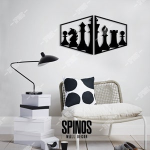 May include: Black metal wall decor featuring a chess piece design. The chess pieces are arranged in a diagonal line, with the king and queen in the centre. The decor is mounted on a white wall, with a white chair and a lamp in the foreground. The text "SPINOS WALL DECOR" is visible at the bottom of the image.