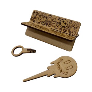 May include: A wooden bench with a smiley face design, a wooden key with a ring, and a wooden smiley face with a dripping design.
