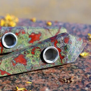 May include: Two green, red, and black crystal pipes with metal bowls. The pipes are made of polished stone and have a unique, natural pattern.