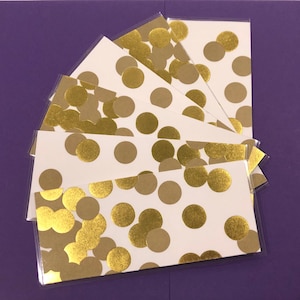 May include: A stack of white cards with a gold and brown polka dot pattern. The cards are arranged in a fan shape.
