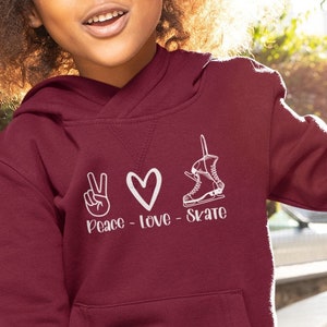 May include: A maroon hoodie with a white peace sign, heart, and ice skate graphic. The text "Peace - Love - Skate" is printed below the graphic.