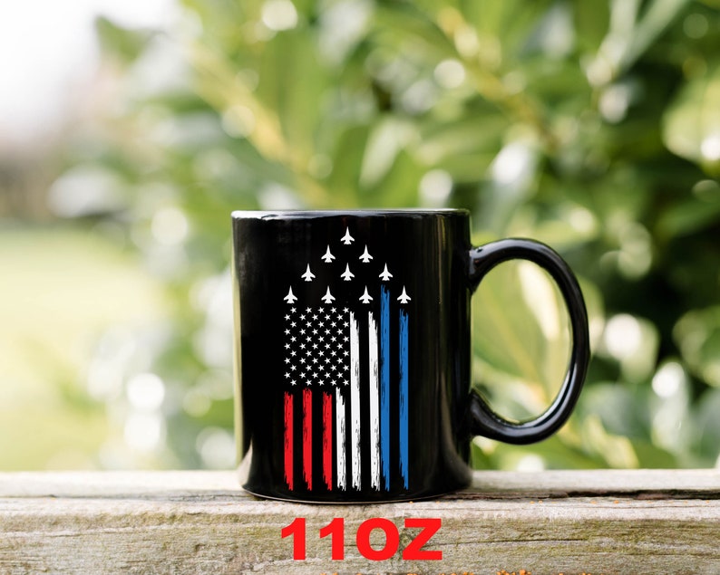 This is a picture of a patriotic coffee mug. The mug is black. The mug has the US flag and a patriotic flyover on one side and on the other side of the mug is a beautiful American Bald Eagle with the American flag