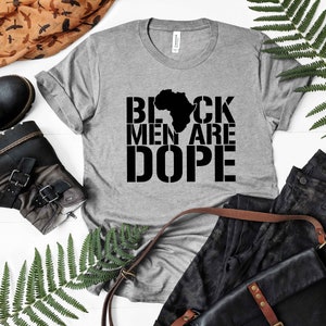 This is a picture of an African American man wearing a Shirt for BLACK MAN. It is a t shirt for aBlack male that says Black Men are DOPE t shirt