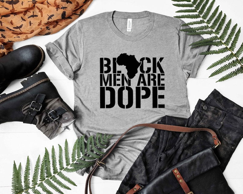 This is a picture of an African American man wearing a Shirt for BLACK MAN. It is a t shirt for aBlack male that says Black Men are DOPE t shirt