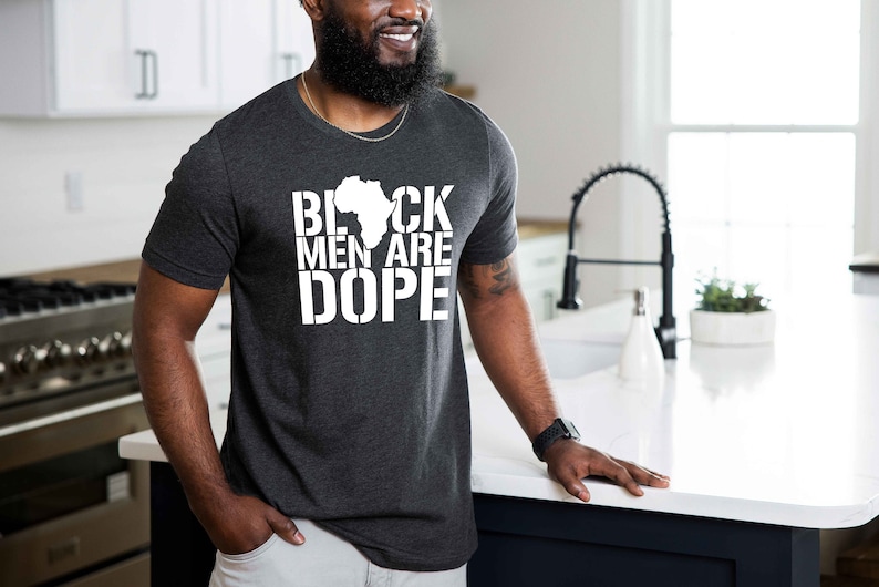This is a picture of an African American man wearing a Shirt for BLACK MAN. It is a t shirt for aBlack male that says Black Men are DOPE t shirt