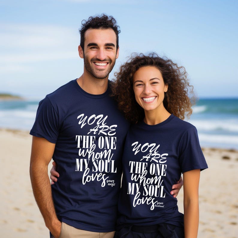 Christian couple matching t shirts with religious quote, smiling husband and wife at beach