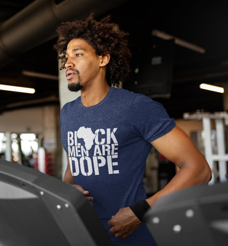 This is a picture of an African American man wearing a Shirt for BLACK MAN. It is a t shirt for aBlack male that says Black Men are DOPE t shirt