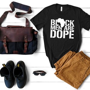 This is a picture of an African American man wearing a Shirt for BLACK MAN. It is a t shirt for aBlack male that says Black Men are DOPE t shirt