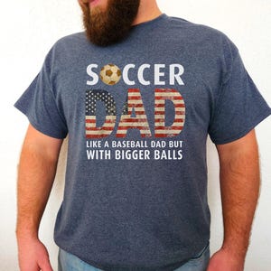 Men’s soccer dad t shirt featuring American flag text and soccer ball graphic, funny soccer dad design on heather navy blue shirt