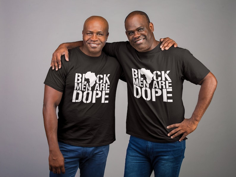 This is a picture of an African American man wearing a Shirt for BLACK MAN. It is a t shirt for aBlack male that says Black Men are DOPE t shirt