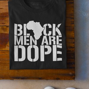 This is a picture of an African American man wearing a Shirt for BLACK MAN. It is a t shirt for aBlack male that says Black Men are DOPE t shirt