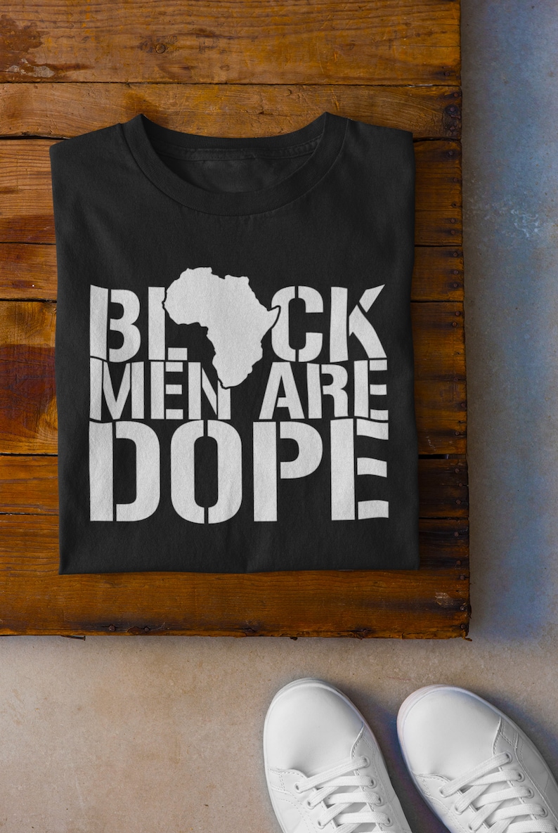 This is a picture of an African American man wearing a Shirt for BLACK MAN. It is a t shirt for aBlack male that says Black Men are DOPE t shirt
