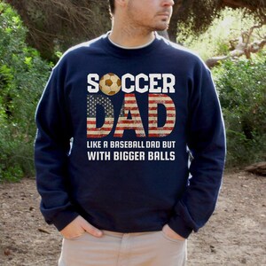Funny soccer dad crewneck sweatshirt with patriotic American flag lettering, men’s soccer dad top worn outdoors