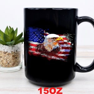 This is a picture of a patriotic coffee mug. The mug is black. The mug has the US flag and a patriotic flyover on one side and on the other side of the mug is a beautiful American Bald Eagle with the American flag