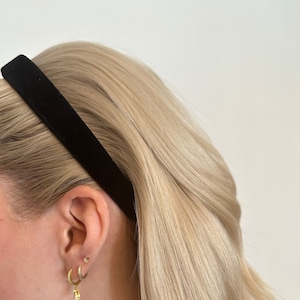 May include: A woman with blonde hair wearing a black velvet headband and gold hoop earrings.