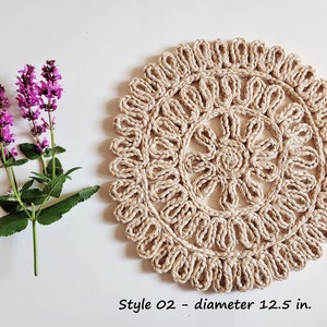 May include: A round, beige, crocheted coaster with a floral design. The coaster is 12.5 inches in diameter. Style 02.