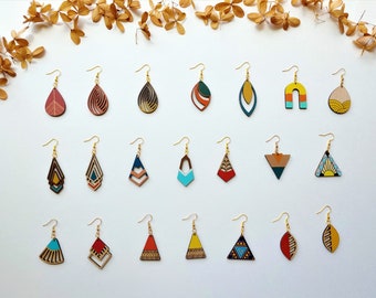 May include: Assortment of 20 pairs of geometric wooden earrings with colorful patterns. The earrings are in various shapes, including teardrops, triangles, arches, and squares.