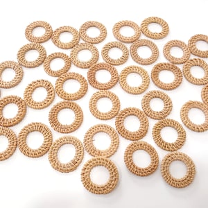 May include: A collection of 30 natural woven rattan rings. The rings are all the same size and are arranged in a circular pattern. They are a light brown color and have a natural, rustic look.